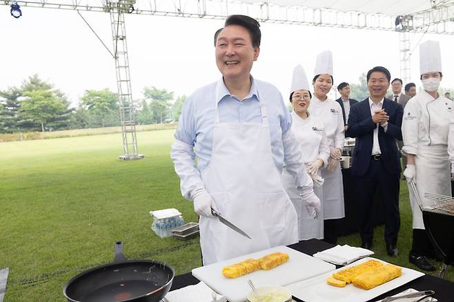 윤석열 대통령이 24일 서울 용산 대통령실 잔디마당에서 열린 `출입기자단 초청 만찬간담회'에서 앞치마를 두르고 계란말이를 만들고 있다. 대통령실 제공