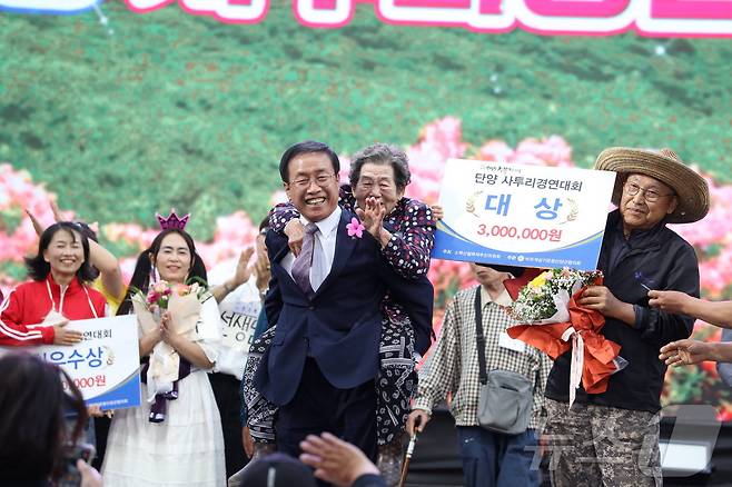 김문근 단양군수(가운데)가 단양사투리경연대회 우승자인 송병선 할머니를 엎고 있는 모습.(단양군 제공)2024.5.26/뉴스1