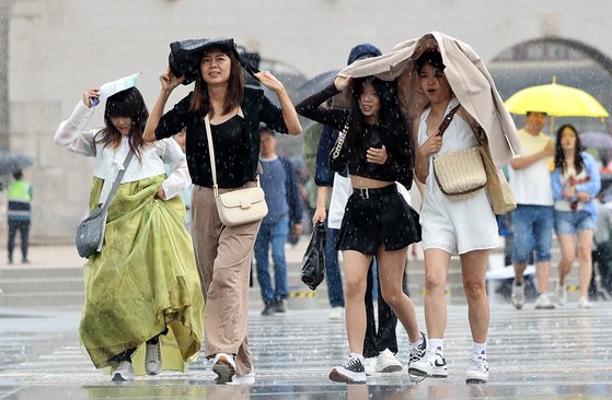 비가 내린 26일 오후 서울 광화문광장 인근에서 외국인 관광객들이 가방과 겉옷으로 비를 피하며 이동하고 있다. 뉴스1