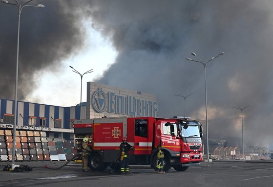 지난 25일(현지시간) 하르키우의 쇼핑센터에 소방관들이 출동해 화재를 진압하고 있다. AFP=연합뉴스