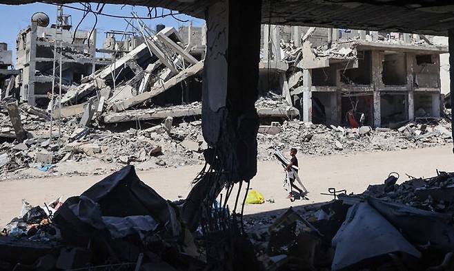 지난 24일(현지시간) 가자지구 남부 칸유니스의 빌딩 잔해들 사이로 한 팔레스타인 소년이 고철을 수집하고 있다. AFP연합뉴스