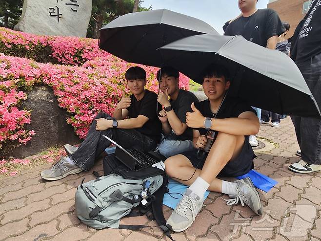 27일 오후 조선대학교에서 이번학기 복학생 박모씨(23·오른쪽)가 중학교 동창들과 우산으로 햇빛을 가린채 뉴진스 뮤직비디오를 보며 입장을 기다리고 있다.2024.5.27./뉴스1 ⓒ News1 서충섭 기자