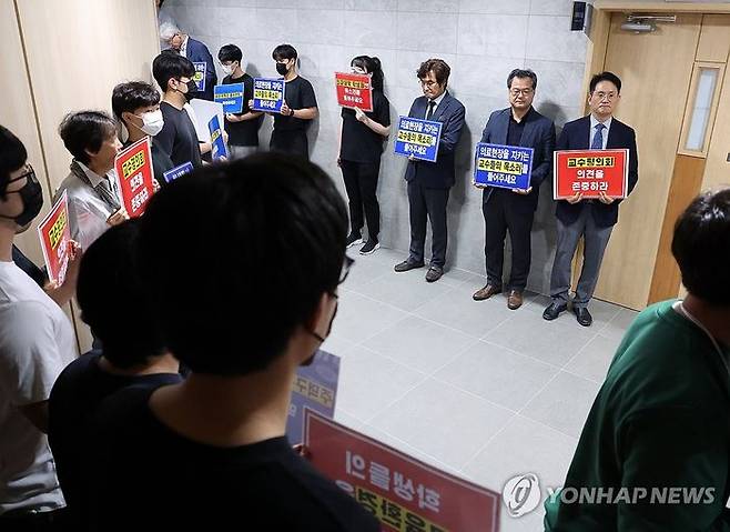 전북대 의대 증원을 위한 학칙 개정안을 심의할 대학평의원회가 열리는 27일 오전, 전북대 대학 본부 앞에 의대 교수와 학생들이 학칙 개정안 부결을 요구하는 손팻말을 들고 있다.ⓒ연합뉴스