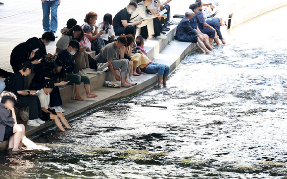 지난 23일 오후 서울 중구 청계천 모전교 아래에서 시민과 외국인 관광객 등이 더위를 식히고 있다. [사진=뉴시스]