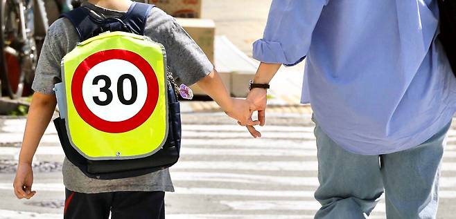 한 어린이가 하굣길에 엄마와 손잡고 횡단보도를 지나가고 있습니다. 책가방에는 제한속도 시속 30㎞ 표지판 모양이 그려져 있습니다. 차 조심, 안전운전 명심해야겠습니다.  김호영 기자