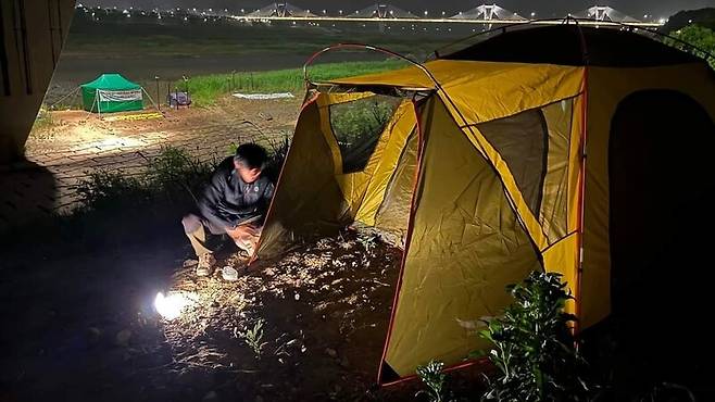 세종시에 비가 예보된 지난달 26일 새벽 이경호 대전환경운동연합 사무처장이 천막농성장이 보이는 맞은편 언덕에 임시 텐트를 치고 있다. 대전충남녹색연합 제공