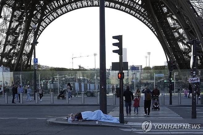 지난 4월 프랑스 파리 에펠탑 옆에서 한 노숙인이 자고 있다. 
[AP 연합뉴스 자료사진. 재판매 및 DB 금지]