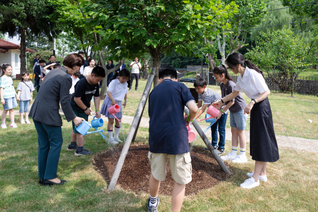 김건희 여사와 한화진 환경부 장관, 어린이들이 5일 서울 용산어린이정원에서 열린 '어린이 환경·생태 교육관' 개관식에서 지난해 방한한 제인구달 박사가 식수한 산사나무에 물을 주고 있다. 연합뉴스