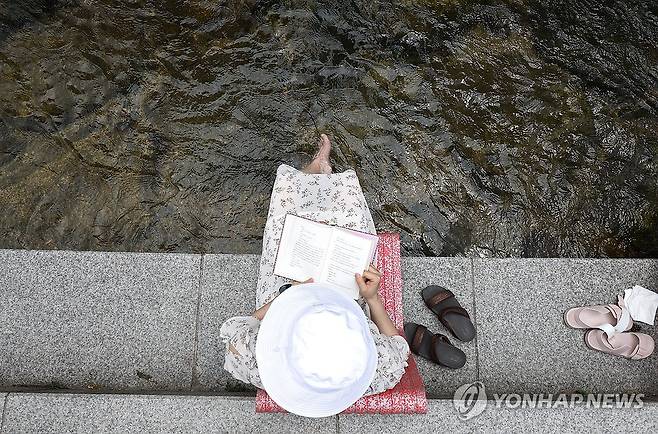 청계천에서 독서를 (서울=연합뉴스) 윤동진 기자 = 무더운 날씨를 보인 6일 오후 서울 청계천을 찾은 한 시민이 시간을 보내고 있다. 2024.6.6 mon@yna.co.kr