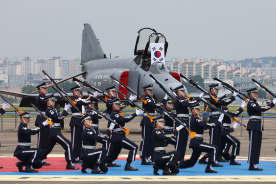 F-4E 진회색 기체가 7일 경기 수원시 공군 10전투비행단에서 열린 F-4 팬텀(Phantom) 퇴역식에 주기된 가운데 공군 의장대가 퇴역식 축하 행진을 펼치고 있다. 사진공동취재단／연합뉴스