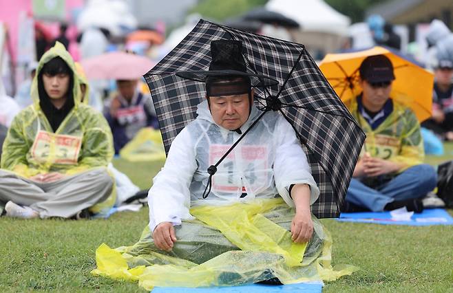 비가 내린 26일 오후 서울 종로구 광화문광장에서 열린 2024 국제 멍때리기 대회에서 참가자들이 우산을 쓰거나 우의를 입고 멍을 때리고 있다. [사진 = 연합뉴스]