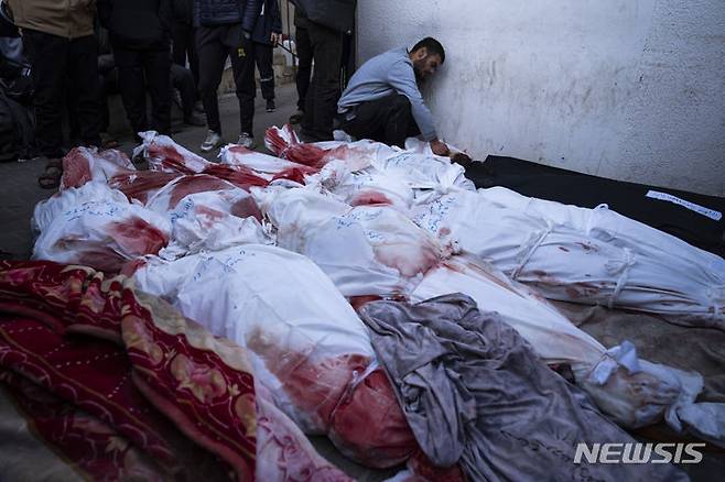 [AP/뉴시스] 지난 2월12일 가자 남단 라파의 병원 안치실에 간밤 이스라엘 군 공격에 사망한 주민들의 시신이 무더기로 놓여 있고 한 가족이 벽에 기대 울고 있다. 이스라엘군은 새벽2시 전투기를 동원해 2명의 인질을 라파 아파트에서 구출하는 데 성공했다. 이때 가자 주민 67명이 사망했다고 가자 보건부는 말했다. 서안지구의 팔레스타인 적신월사 및 하마스는 사망자가 100명이 넘는다고 주장했다. 2024. 02. 12.