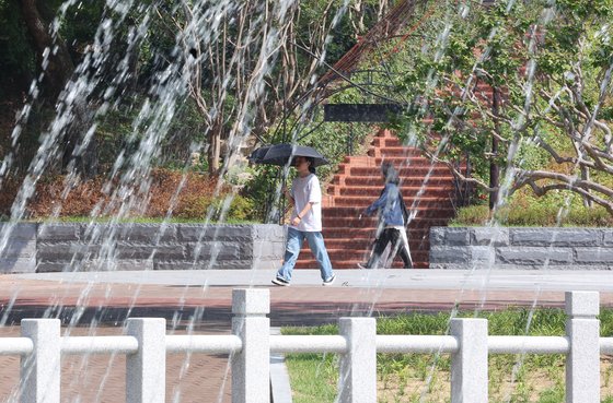 11일 폭염주의보가 발령된 대구 낮 최고기온이 34도로 예보된 가운데 경북대학교 분수 옆으로 햇빛을 가리기 위해 양산을 든 시민이 지나가고 있다. 연합뉴스