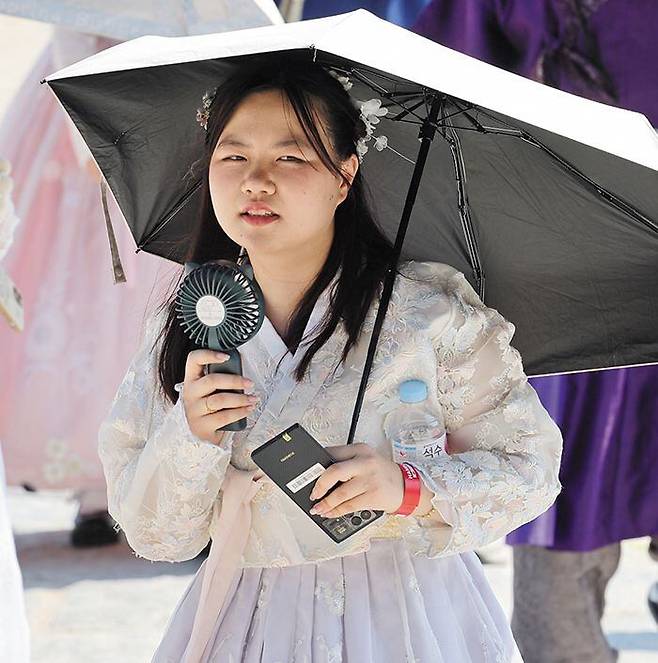 13일 오후 서울 경복궁에서 외국인 관광객이 양산을 쓰고 휴대용 선풍기를 들고 있다. /연합뉴스