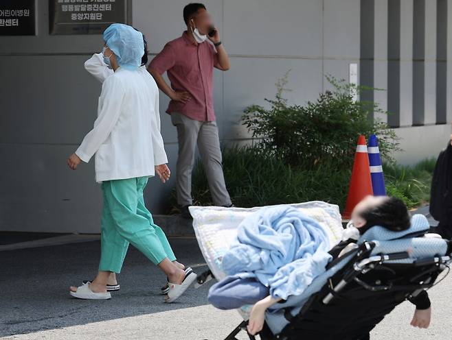 A medical worker walks near a paediatric patient at Seoul National University Hospital in Jongno-gu, Seoul, where an indefinite collective shutdown is expected on Monday. (Yonhap)