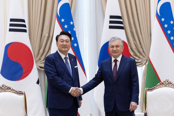 President Yoon Suk Yeol, left, and Uzbek President Shavkat Mirziyoyev shake hands at their bilateral summit at the presidential palace in Tashkent, Uzbekistan, on Friday. [PRESIDENTIAL OFFICE]