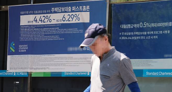 서울 한 시중은행 영업점의 대출 안내문 앞을 시민이 지나가고 있다.[연합]