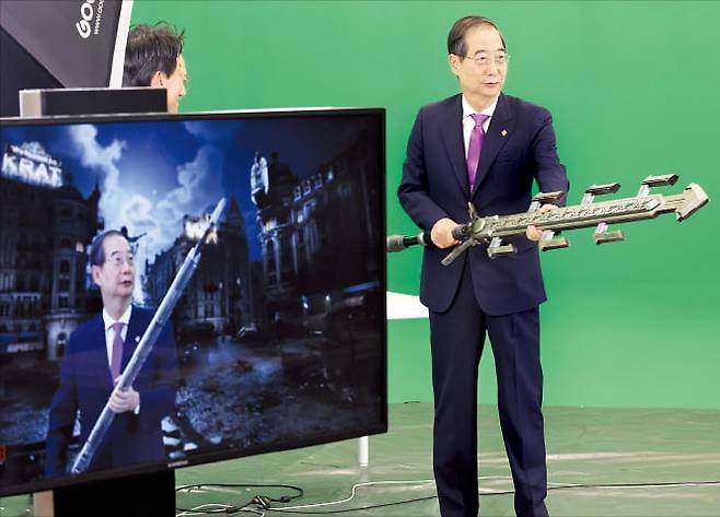 한덕수 국무총리가 18일 경기 성남시 판교 네오위즈를 방문해 ‘P의 거짓’ 게임 속 아이템을 들고 크로마키 촬영 체험을 하고 있다.  연합뉴스