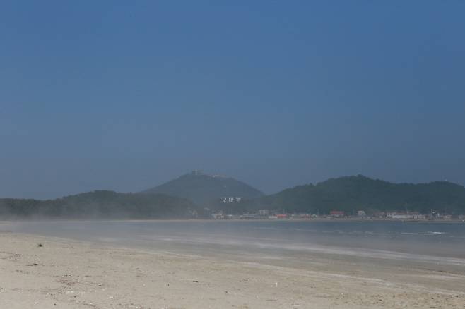 해무가 자욱하게 낀 모래 해안에서 바라본 용기포항, 백령도의 말은 본래 쓰이던 황해도 말과 용기포항으로 드나드는 남쪽의 말이 섞이면서 한치 앞을 볼 수 없는 안개에 휩싸여 있다. 그러나 백령도에서의 언어 융합은 통일 이후 한국어의 선례가 될 수 있다. 한성우 제공