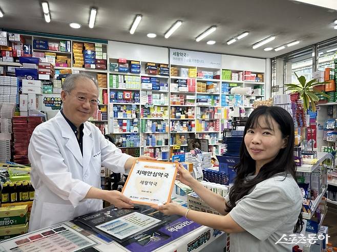 대구 수성구 치매안심센터 관계자가 치매안심약국에 현판을 전달하고 있다./사진=수성구