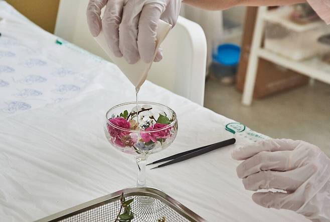 부케 꽃잎을 유리잔에 붙이고 오래 보존할 수 있도록 젤레진이라는 보존액을 첨가하고 있는 모습. 스튜디오 어댑터 경지은