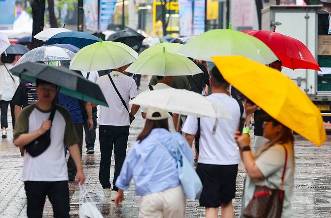 비가 내린 22일 오전 서울 명동거리에 시민들과 관광객들이 우산을 쓰고 이동하고 있다, [연합]