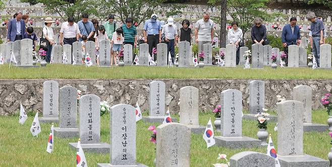 6.25전쟁의 날 74주년을 이틀 앞둔 23일 서울 동작구 국립서울현충원에서 청주 곽씨 종친회 회원들이 묘역 앞에서 묵념을 하고 있다.