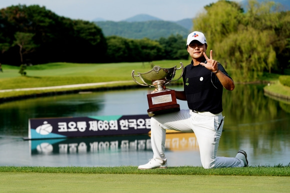 김민규가 23일 충남 천안 우정힐스 컨트리클럽에서 막을 내린 코오롱 제66회 한국오픈골프선수권대회에서 1위를 차지한 뒤 우승컵을 무릎 위에 올린 채 손가락 3개를 펼쳐 보이며 통산 3승을 알리고 있다. 코오롱 한국오픈 조직위원회 제공