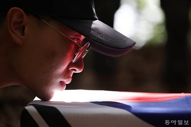 6.25 전쟁 74주년을 하루 앞둔 24일 국방부 유해발굴감식단 이준하 상병이 경기도 파주시 광탄면 돌봉산 150고지에서 국군 전사자 유해가 발굴될 것을 대비해 태극기로 오동나무 관을 감싸는 관포의식을 연습하고 있다. 의식을 행하는 장병들은 관에 얼굴을 가까이 붙여 틀어진 부분과 주름진 곳이 없는지 확인한다. 유해발굴감식단은 지난 5월 13일부터 이 지역 일대에서 발굴 작전을 이어가고 있다. 파주=박형기 기자 oneshot@donga.com