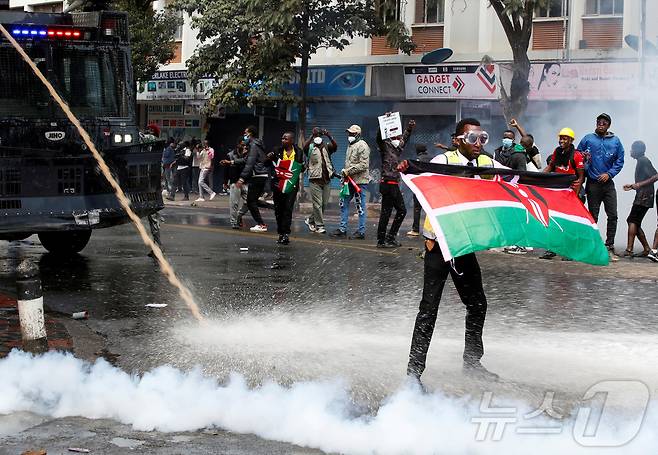 케냐 정부의 증세 정책에 반대하는 시민들이 25일(현지시간) 나이로비 거리로 나와 격렬한 시위를 벌이고 있다. 물대포와 최루탄을 사용하는 경찰 앞에서 케냐 국기를 흔드는 시민의 모습. 2024.06.25 ⓒ 로이터=뉴스1 ⓒ News1 임여익 기자