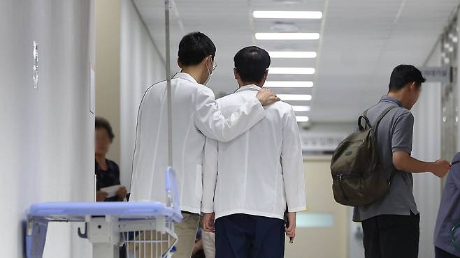 정부의 의대 증원 정책에 반대하는 전공의들의 집단 이탈 상황이 이어지고 있는 25일 대구 한 대학병원에서 의사가 동료 의사의 어깨를 다독이고 있다./연합뉴스