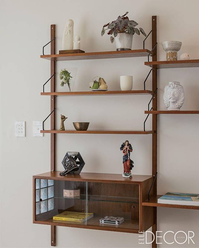 거실 벽에 시공한 모듈형 월 시스템에는 부부가 시칠리아에서 구입한 공예품부터 혜미 작가의 도예 작품까지 다양한 수집품을 올려놓았다.