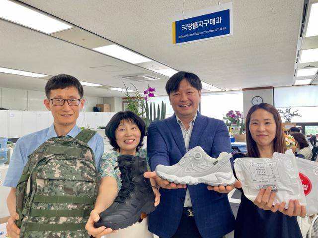 군 장병들이 먹고 입고 쓰는 군수품들을 구매해 공급하는 조달청 국방물자구매과의 권수헌(왼쪽부터) 사무관과 김민지 서기관, 김명균 과장, 이형진 주무관이 샘플 제품들을 들어 보이며 활짝 웃고 있다.이들은 물품 구매 방식, 규정 개선을 통해 같은 예산으로 더 좋은 물품을 조달할 수 있다고 강조한다.
