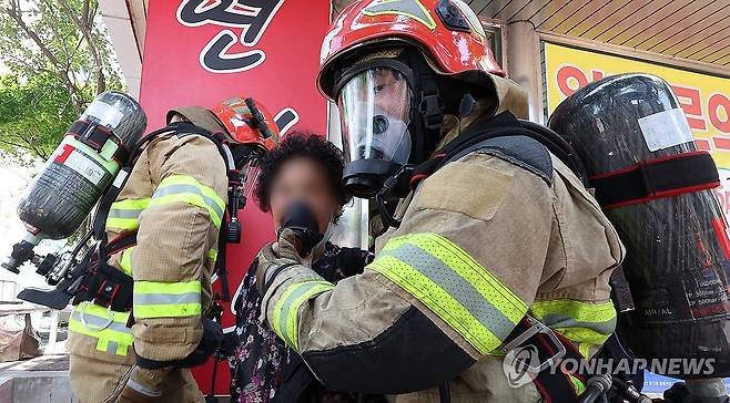 화재 건물서 구조되는 시민 (대구=연합뉴스) 윤관식 기자 = 28일 오후 대구 동구 한 복합건축물에서 화재가 발생한 가운데 소방대원이 옥상으로 대피해 있던 시민을 공기 보조마스크를 씌워 건물 바깥으로 대피시키고 있다.
    이 화재로 6명이 다치고 42명이 한때 옥상에 대피했다. 2024.6.28 psik@yna.co.kr