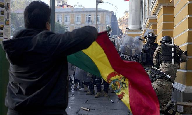이스 아르세 볼리비아 대통령의 지지자가 26일(현지시각) 라파스의 대통령궁에서 철수하는 볼리비아 군인들을 보면서 국기를 흔들고 있다. AP연합뉴스