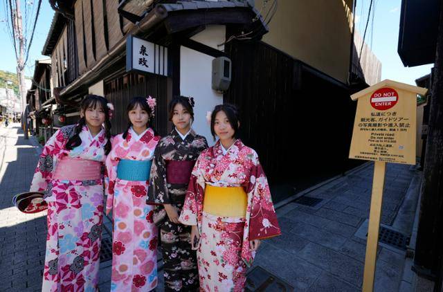 일본 교토를 찾은 대만 관광객들이 지난달 29일 교토 대표 관광지 기온 골목 입구에 세워진 '골목길 출입 제한' 푯말 옆에서 포즈를 취하고 있다. 교토=EPA 연합뉴스