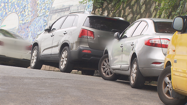 공원  진입로에 가득 찬 주차 차량. 일부만 바퀴를 돌려놨다.