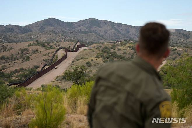 [AP/뉴시스] 지난 6월 미국의 멕시코 접경 남부 국경일부인 애리조나주 나갈리즈에서 한 미국 국경수비대 요원이 국경을 바라보고 있다