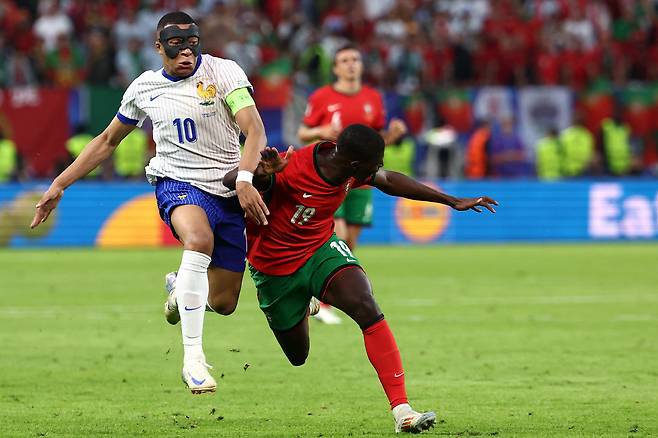 France's forward #10 Kylian Mbappe (L) fights for the ball with Portugal's defender #19 Nuno Mendes during the UEFA Euro 2024 quarter-final football match between Portugal and France at the Volksparkstadion in Hamburg on July 5, 2024. (Photo by FRANCK FIFE / AFP)<저작권자(c) 연합뉴스, 무단 전재-재배포, AI 학습 및 활용 금지>