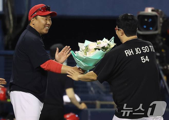 10일 오후 서울 송파구 잠실야구장에서 열린 프로야구 '2024 신한 SOL 뱅크 KBO리그' KIA 타이거즈와 LG 트윈스의 경기, 5대2 승리를 거둔 KIA 이범호 감독이 이날 선발 등판으로 KBO리그 최초로 400경기 등판 신기록과 함께 4회말 선두 타자 오스틴 딘을 투수 직선타로 잡아내 올 시즌 100이닝을 채우면서 역대 3번째로 11시즌 연속 100이닝 기록을 세운 양현종에게 꽃다발을 전달하고 있다. 2024.7.10/뉴스1 ⓒ News1 김진환 기자