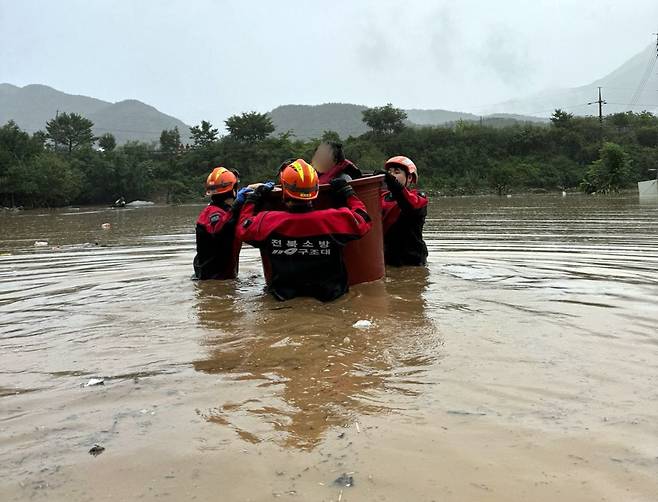 10일 오전 내린 폭우로 전북 완주군 운주면 한 마을 주민들이 고립되자 119구조대원들이 몸이 불편한 주민을 고무통에 태워 구조하고 있다. /전북소방본부