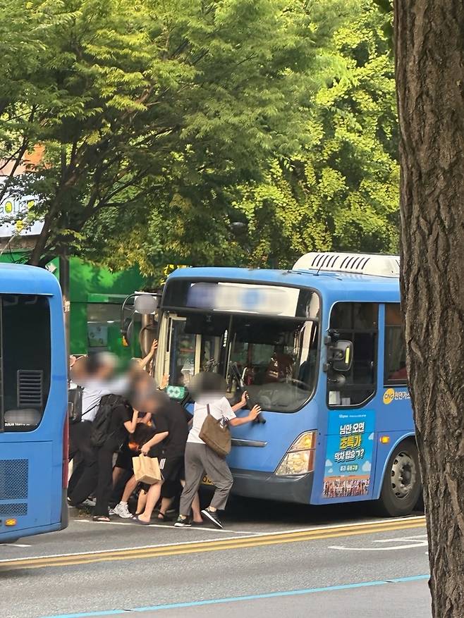 홍제역 인근 버스정류장에서 시민들이 여성을 구조하기 위해 버스를 들어올리고 있다. [사진 = 독자 제공, 연합뉴스]