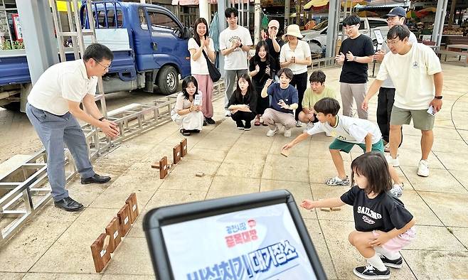 지난달 29일 광천전통시장의 시장탈출게임 ‘골목대장2’에 참가한 시형·예솔 남매가 관람객들의 응원을 받으며 비석치기 게임을 하고 있다. 송인걸 기자