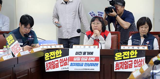 최저임금위원회 근로자 위원들이 9일 오후 정부세종청사 최저임금위원회에서 열린 제9차 전원회의에서 ‘온전한 최저임금 인상’을 요구하는 피켓을 걸어놓고 있다. [사진출처 = 연합뉴스]