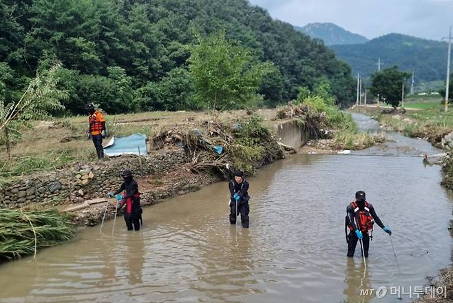 [영동=뉴시스] 안성수 기자 = 12일 집중호우 실종 사고가 난 충북 영동군 심천면 하천 인근에서 경찰, 소방당국이 실종자 수색 작업을 벌이고 있다. 지난 10일 오전 5시10분께 심천면 법곡저수지 붕괴로 주거용 컨테이너에 있던 70대 남성이 실종됐다. (사진=영동소방서 제공) 2024.7.12. photo@newsis.com  *재판매 및 DB 금지 /사진=안성수