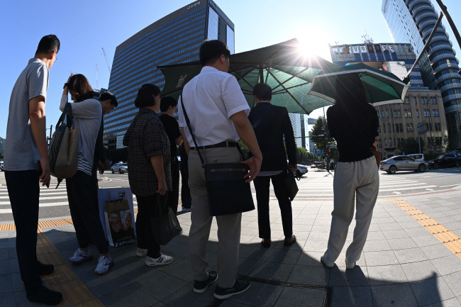 출근길은 ‘쨍쨍’ 수도권에 폭염과 소나기가 예보된 15일 오전 서울 종로구 세종대로 사거리에서 시민들이 그늘에서 보행 신호를 기다리고 있다.  문호남 기자