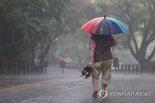 전국 곳곳에 비가 내린 16일 오후 서울 남산을 찾은 시민이 신발을 손에 들고 하산하고 있다. [연합뉴스]