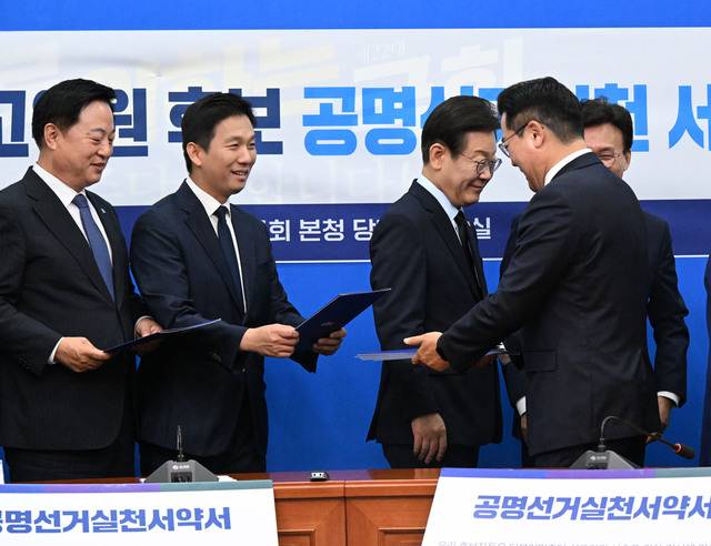 더불어민주당 8·18 당대표 선거에 출마한 이재명 김지수 김두관 후보(오른쪽 세 번째부터)가 15일 서울 여의도 국회에서 열린 공명선거실천 서약식에 참석해 서명한 서약서를 박찬대 원내대표에게 전달하고 있다. 이병주 기자