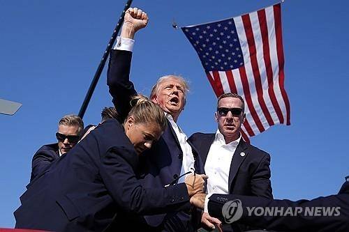 지난 13일(현지시간) 미국 펜실베이니아 버틀러 유세에서 총격을 당한 트럼프 전 대통령이 단상에서 내려오며 주먹을 머리 위로 쥐어 보이고 있다.