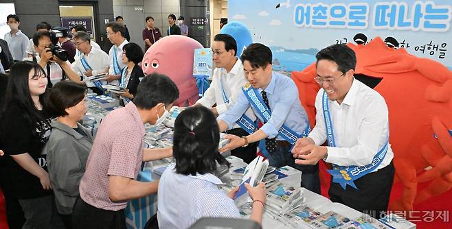 강도형(오른쪽부터) 해양수산부 장관, 방송인 남희석, 노동진 수협 회장이 16일 오후 서울 강남구 SRT 수서역 맞이방에서 열린 ‘여름휴가 어촌에서 보내기 캠페인’ 행사에 참석해 시민들에게 어촌 여행지 책자를 배포하고 있다. 임세준 기자